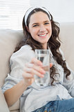 Gorgeous casual woman on cosy couch holding water