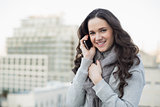 Smiling pretty brunette in winter clothes having phone call