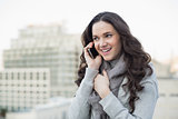 Cheerful pretty brunette in winter clothes having phone call