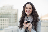 Cheerful pretty brunette sending a text on her smartphone