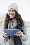 Cheerful pretty brunette holding her tablet computer