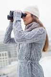 Gorgeous woman with winter clothes on looking through binoculars