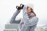 Pretty woman with winter clothes on looking through binoculars