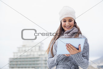 Smiling woman with winter clothes on using her tablet