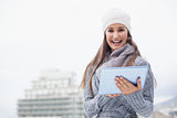 Cheerful woman with winter clothes on using her tablet
