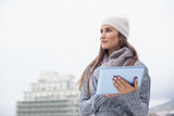 Pensive woman with winter clothes on using her tablet