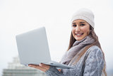 Smiling gorgeous woman with winter clothes on using her laptop