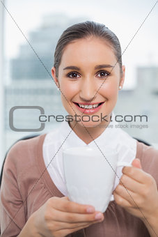 Happy gorgeous businesswoman holding cup of coffee