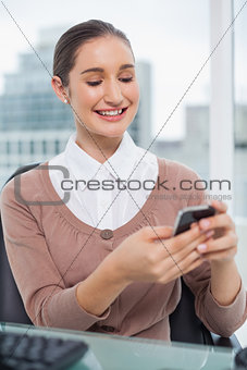 Smiling beautiful businesswoman text messaging