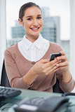 Cheerful beautiful businesswoman text messaging