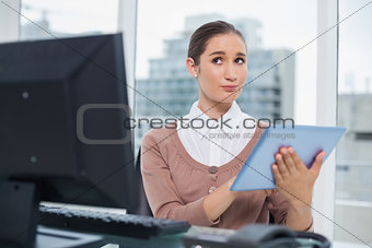 Thoughtful beautiful businesswoman using her tablet