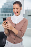 Cheerful classy businesswoman looking at her phone