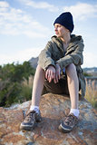 Woman wearing cap sitting on a rock
