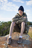 Smiling woman wearing cap sitting on a rock