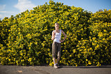 Hiking woman posing beside yellow flowers