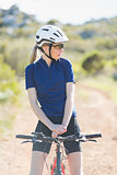 Woman with helmet sitting on bike and looking away