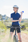 Happy woman with bike holding bottle