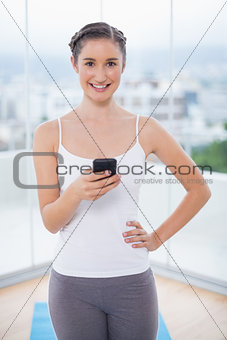 Smiling sporty brunette text messaging