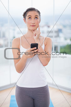 Thoughtful sporty brunette text messaging
