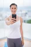 Smiling sporty brunette holding her phone