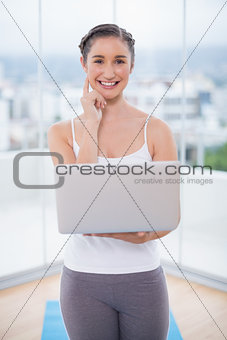 Happy sporty brunette using her laptop