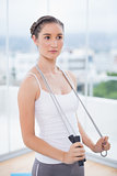 Pensive sporty woman holding skipping rope