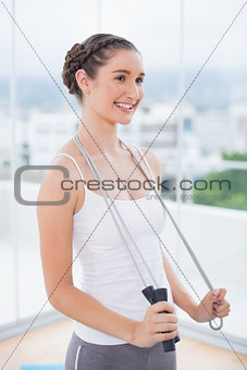 Cheerful sporty brunette holding skipping rope