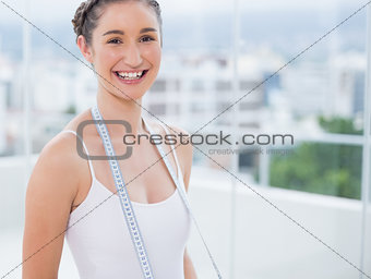 Cheerful sporty brunette holding measuring tape