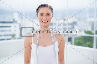 Happy sporty brunette holding measuring tape