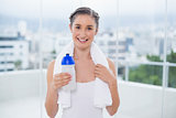 Happy sporty brunette holding towel and flask