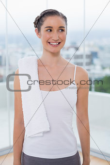 Smiling sporty brunette with white towel on shoulder