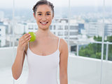 Smiling sporty brunette holding green apple