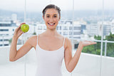 Cheerful sporty brunette holding green healthy apple