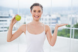 Happy sporty woman holding green apple