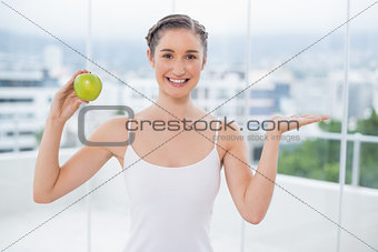 Happy sporty woman holding green apple