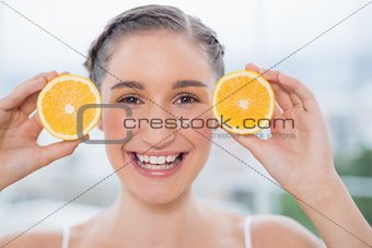 Smiling healthy brunette holding orange slices