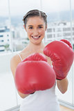 Cheerful sporty brunette wearing red boxing gloves