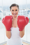 Cheerful sporty brunette wearing boxing gloves