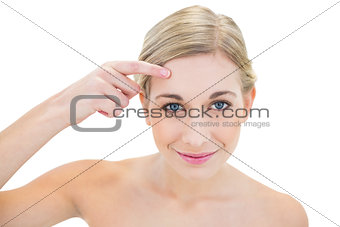 Content young blonde woman pointing her brow with her finger
