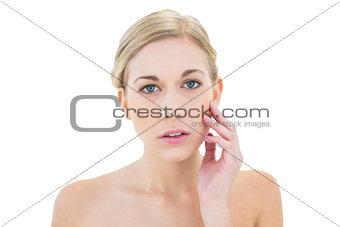 Serious young blonde woman posing touching her cheek