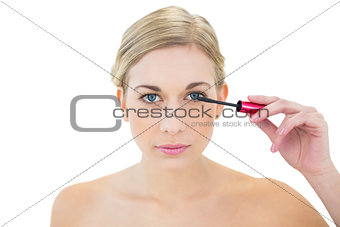 Concentrated young blonde woman applying mascara