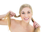 Cheerful young blonde woman holding her pigtails