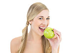 Smiling young blonde woman eating an apple