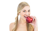 Pleased young blonde woman eating a red apple