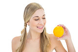 Pleased young blonde woman looking at an orange