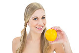 Smiling young blonde woman holding an orange