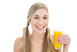 Delighted young blonde woman holding a glass of orange juice