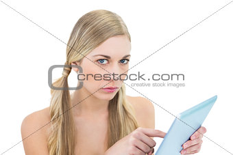 Stern young blonde woman holding a tablet pc