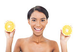 Cheerful attractive model holding slices of orange in both hands