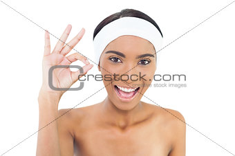 Smiling gorgeous model wearing headband giving okay gesture